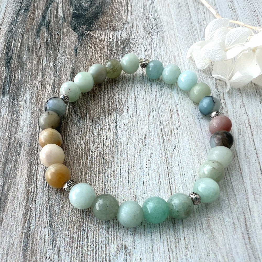 Multicolored beaded bracelet on a textured surface with a white flower.