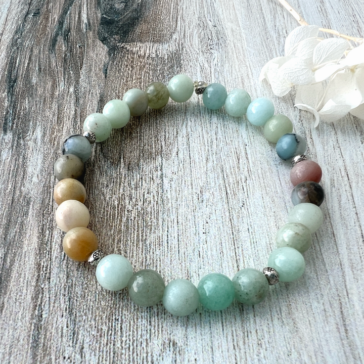 Multicolored beaded bracelet on a textured surface with a white flower.