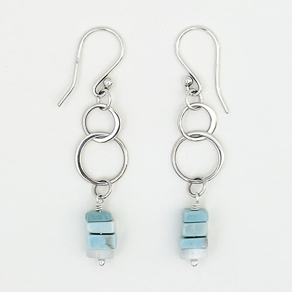 Elevate your style with these stunning sterling silver double-circle drop earrings, adorned with vibrant Natural Ice Blue Larimer heishi beads that add a captivating color pop. These earrings are sure to catch attention and be a delightful addition to any outfit, whether it's for a special occasion or a casual day out.