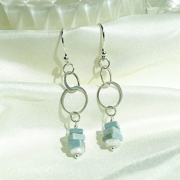 Elevate your style with these stunning sterling silver double-circle drop earrings, adorned with vibrant Natural Ice Blue Larimer heishi beads that add a captivating color pop. These earrings are sure to catch attention and be a delightful addition to any outfit, whether it's for a special occasion or a casual day out.