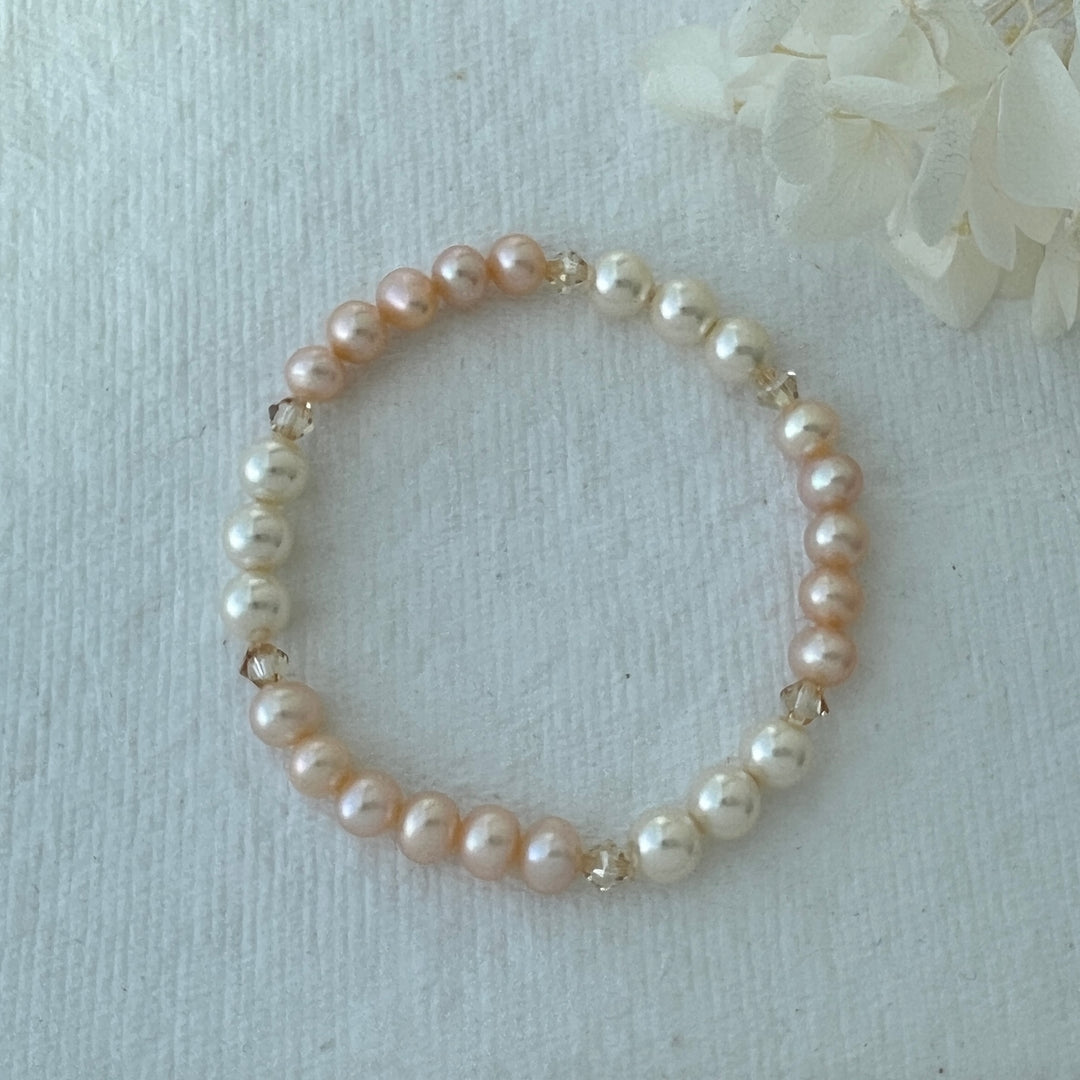 Pearl bracelet on a white paper background with white flowers
