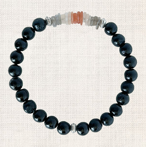 Protect your soul with a cosmic shield of heavenly hues! This vibrant bracelet features a beautiful combination of peach, grey, and white moonstones joined by black tourmalines, thought to provide protection for the wearer.