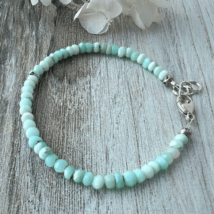 Peruvian Blue Opal beaded bracelet with a sterling silver lobster clasp on a wooden surface