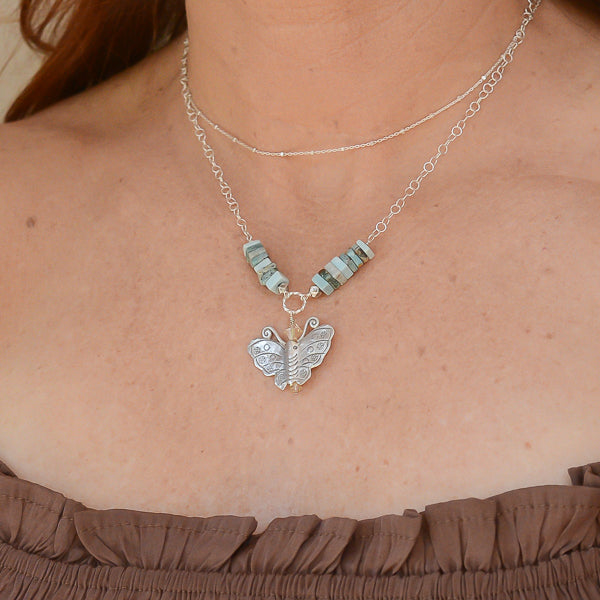The Butterfly Bliss & Larimar Silver Necklace is worn layers with a sterling silver choker chain.
