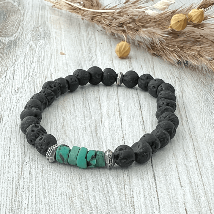 Black lava rock beaded bracelet with green turquoise beads on soft wood surface.