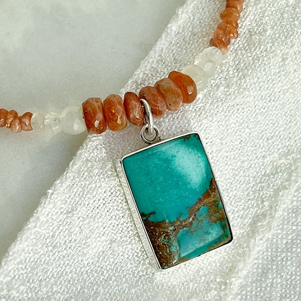 Turquoise stone set in fine & sterling silver. Close-up of pendant showing the copper-orange matrix of the turquoise stone. Handcrafted by Novaura Jewelry of California.