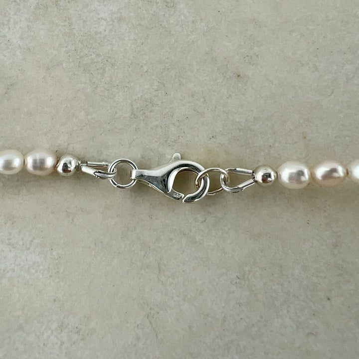 Pearl necklace with silver clasp on a beige background
