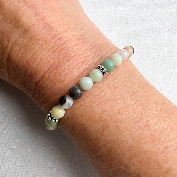 Need a little peaceful energy in your life? Try this Amazonite stretch bracelet with gems showing beautiful green and blue colors with the addition of black and gold hues. A comfortable stretch bracelet to add to your wrist stack. Worn on wrist.