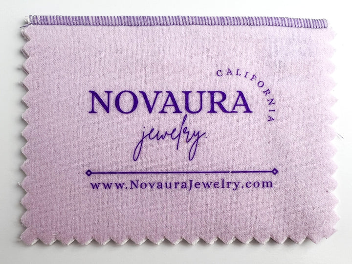 The two-piece Novaura Jewelry Polishing Cloth cleans, polishes, and prevents tarnish ten times longer! The inner white cloth gently and thoroughly cleans and removes tarnish, fingerprints, and body oils while also imparting a tarnish resistant barrier. The outer cloth buffs jewelry to a beautiful luster.