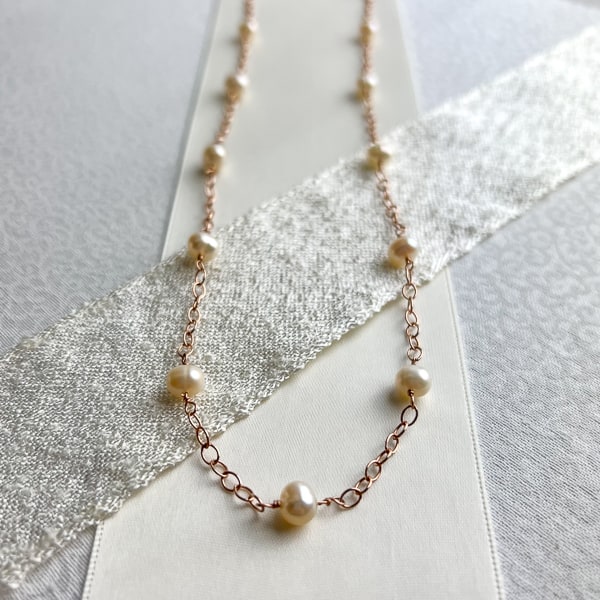 Capture a timeless elegance with this handcrafted freshwater semi-round cream rose pearl necklace. Crafted with 14Kt rose gold-filled chain, this necklace is sure to make a statement whether it's paired with a dressy evening gown or casual everyday attire. Whether you want to treat yourself or surprise that special someone, this necklace is the perfect addition to any jewelry collection.