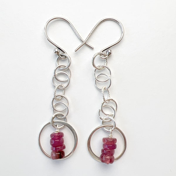 Discover the natural radiance and rainbow of colors of this tantalizing gemstone.   Stunning Tourmalines in raspberry pink are lovingly encircled with sterling silver and hang delicately from intertwining chains. Elevate your casual Friday look with these lightweight earrings that shimmer in the sunlight..Ear wire detail view.