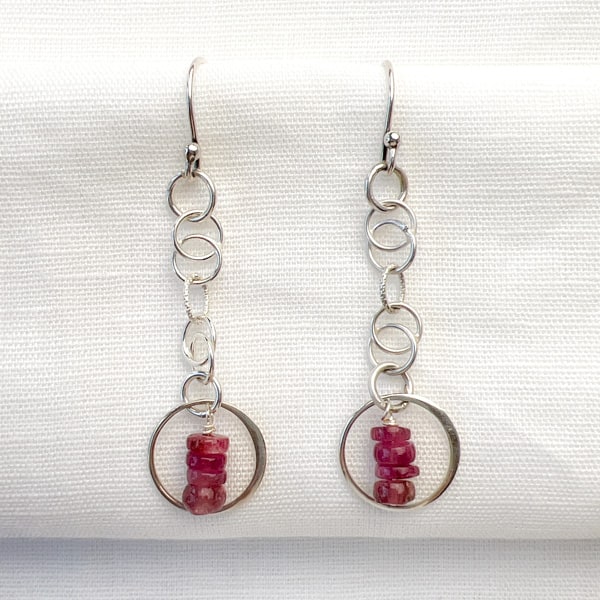 Discover the natural radiance and rainbow of colors of this tantalizing gemstone.   Stunning Tourmalines in raspberry pink are lovingly encircled with sterling silver and hang delicately from intertwining chains. Elevate your casual Friday look with these lightweight earrings that shimmer in the sunlight.