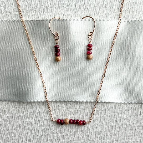 Delicate genuine Ruby gemstone and 14Kt Rose Gold-filled bar necklace and earrings. The shine of the Rose Gold stardust bead compliments the red rubies nicely and gives the necklace an air of sophistication. The queen of gems in a well-polished deep red and hand-cut rondelle shape. 