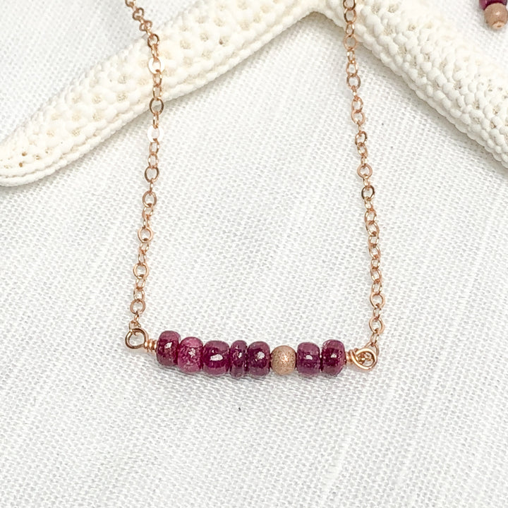 Delicate genuine Ruby gemstone and 14Kt Rose Gold-filled bar necklace. Perfect alone or for layering. The shine of the Rose Gold stardust bead compliments the red rubies nicely and gives the necklace an air of sophistication. The queen of gems in a well-polished deep red and hand-cut rondelle shape. Handcrafted in CA Ruby detail view